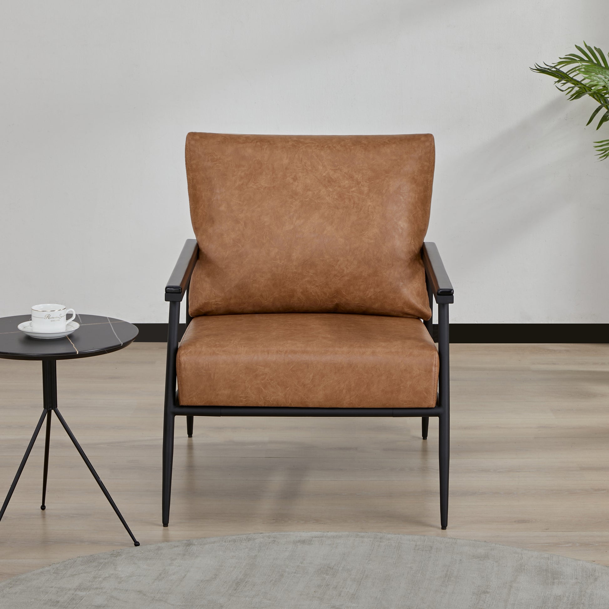 Parker Accent Chair in Faux Leather Light Brown displayed in a modern room with a side table, white wall, and light brown faux leather upholstery