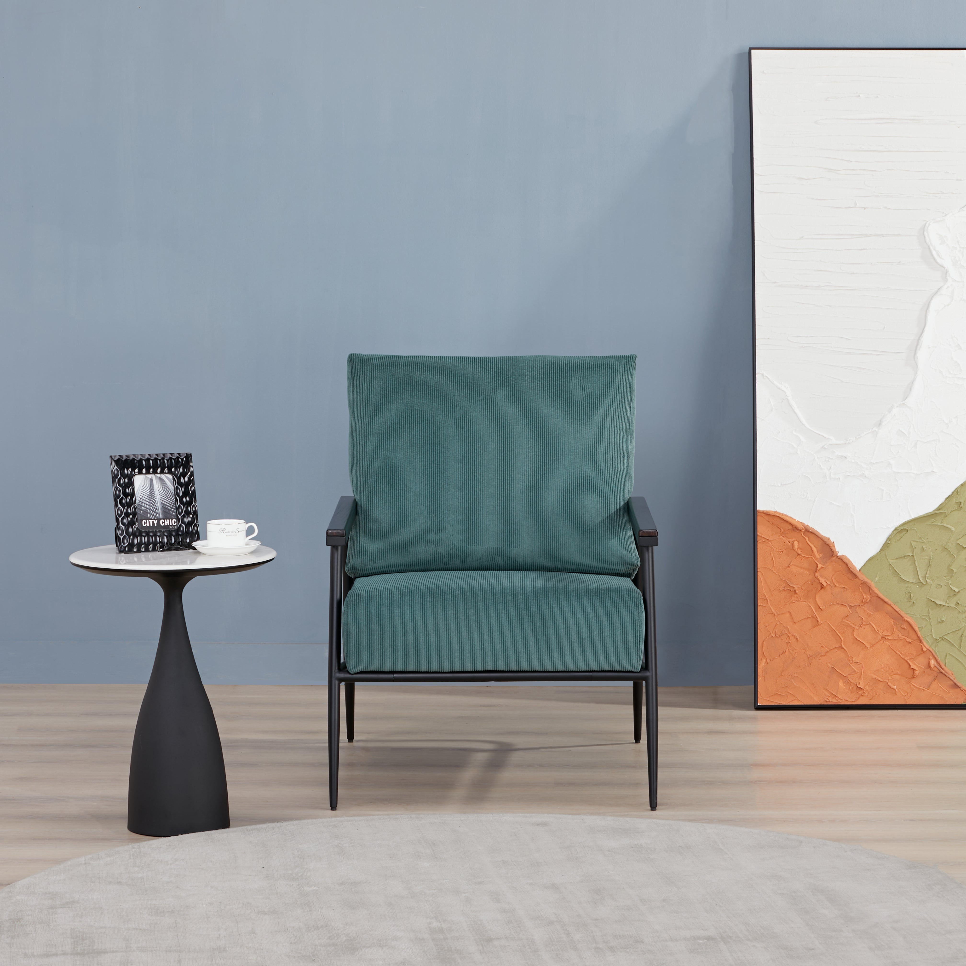 Parker Accent Chair in Corduroy Green displayed in a modern room with a side table, blue wall, abstract artwork, and ribbed green upholstery