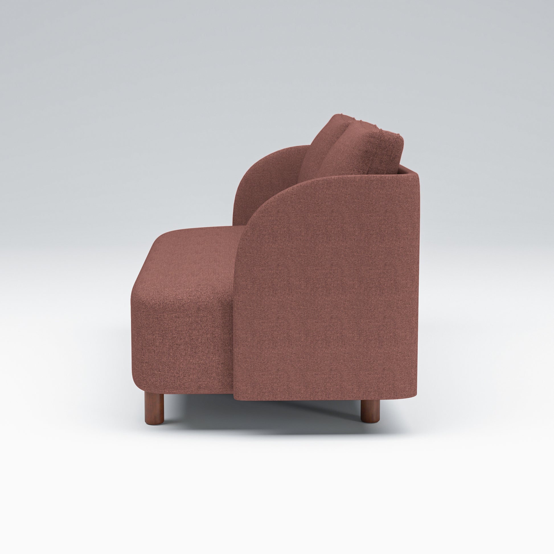 Nora Loveseat in Dusty Rose shown from the side, revealing its deep seat, softly curved arm profile, loose back cushions, and compact brown legs