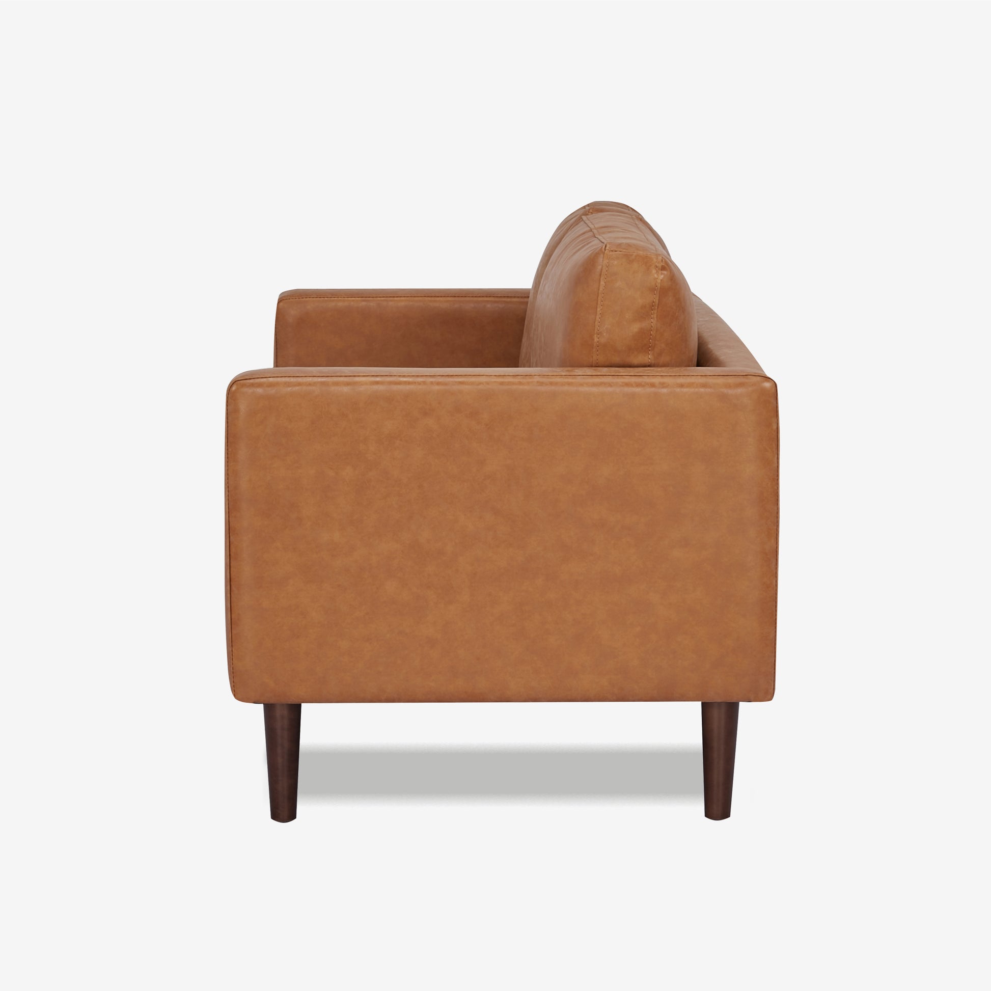 Orlando Loveseat in Faux Leather Camel shown from the side with a deep seat, upright track arm, loose back cushion, visible stitching, and dark brown legs.