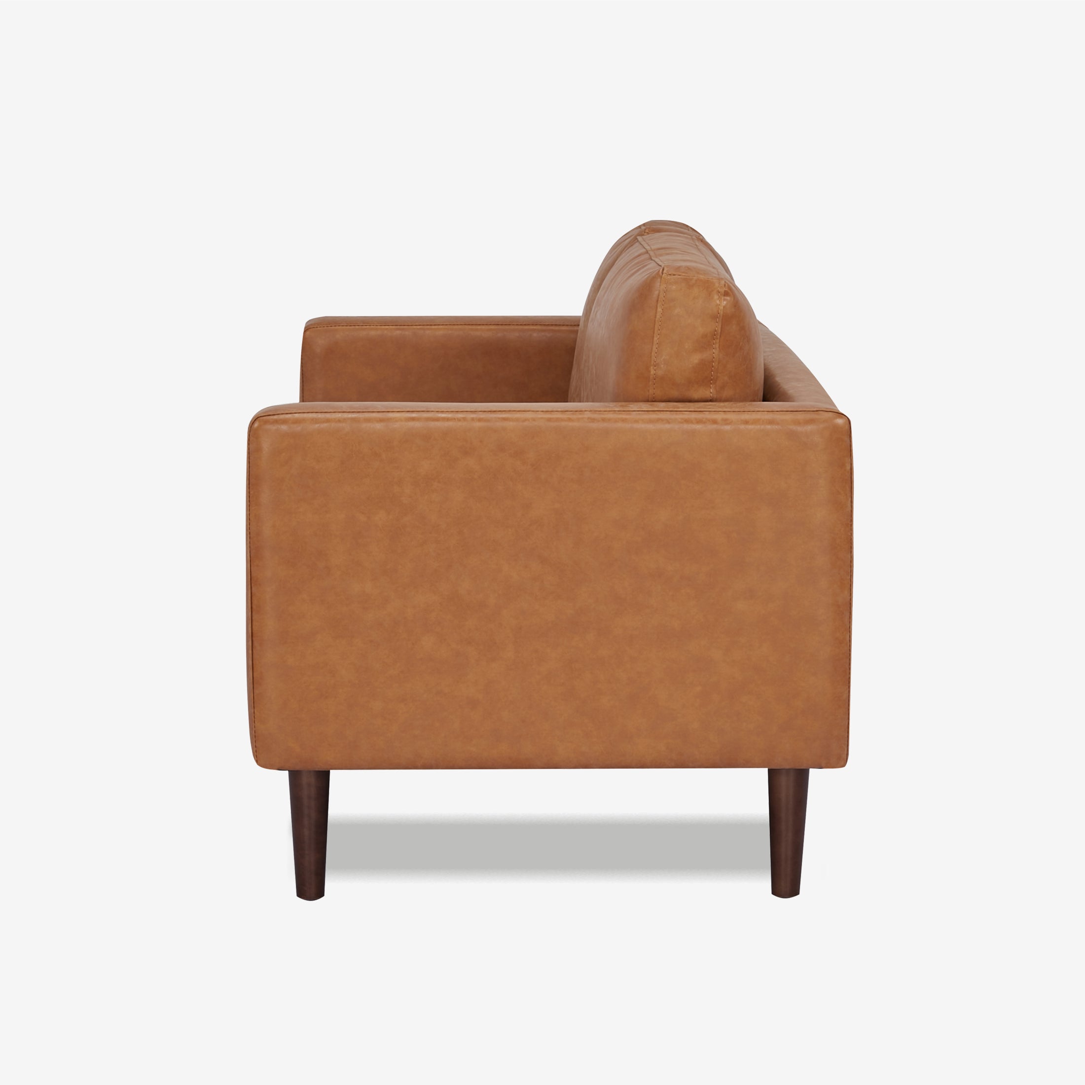 Orlando Loveseat in Faux Leather Camel shown from the side with a deep seat, upright track arm, loose back cushion, visible stitching, and dark brown legs.