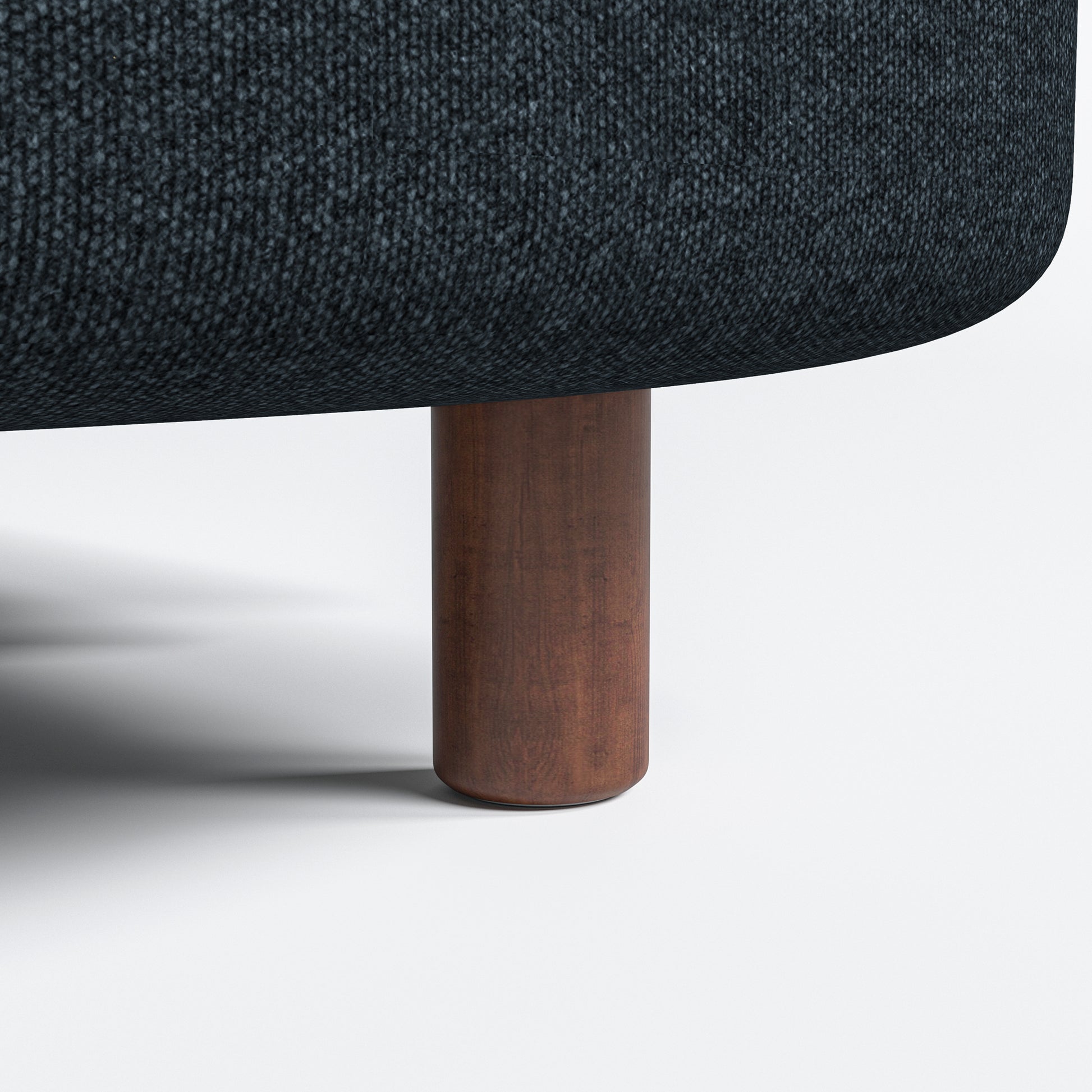 Nora Loveseat in Navy Blue featuring a close-up of the short brown cylindrical leg beneath the rounded base and dark woven upholstery