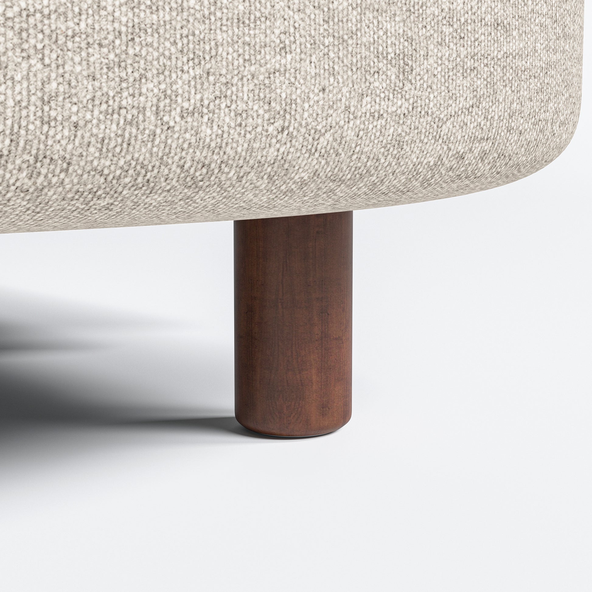 Nora Loveseat in Sandstone Beige featuring a close-up of the short brown leg beneath the rounded upholstered base and beige woven fabric.