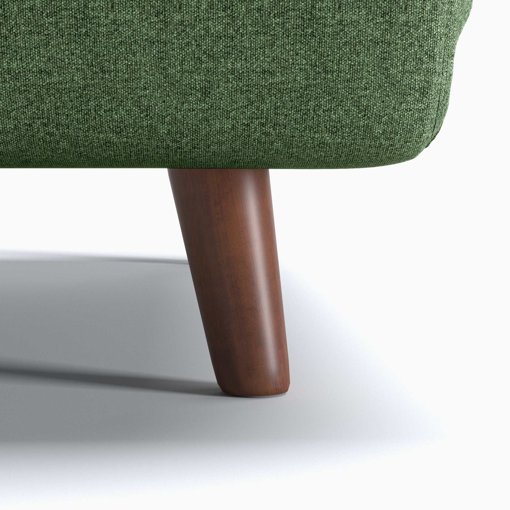Tustin Convertible Chair in Green featuring a close-up of the tapered dark brown wood leg beneath the rounded base and textured green upholstery.