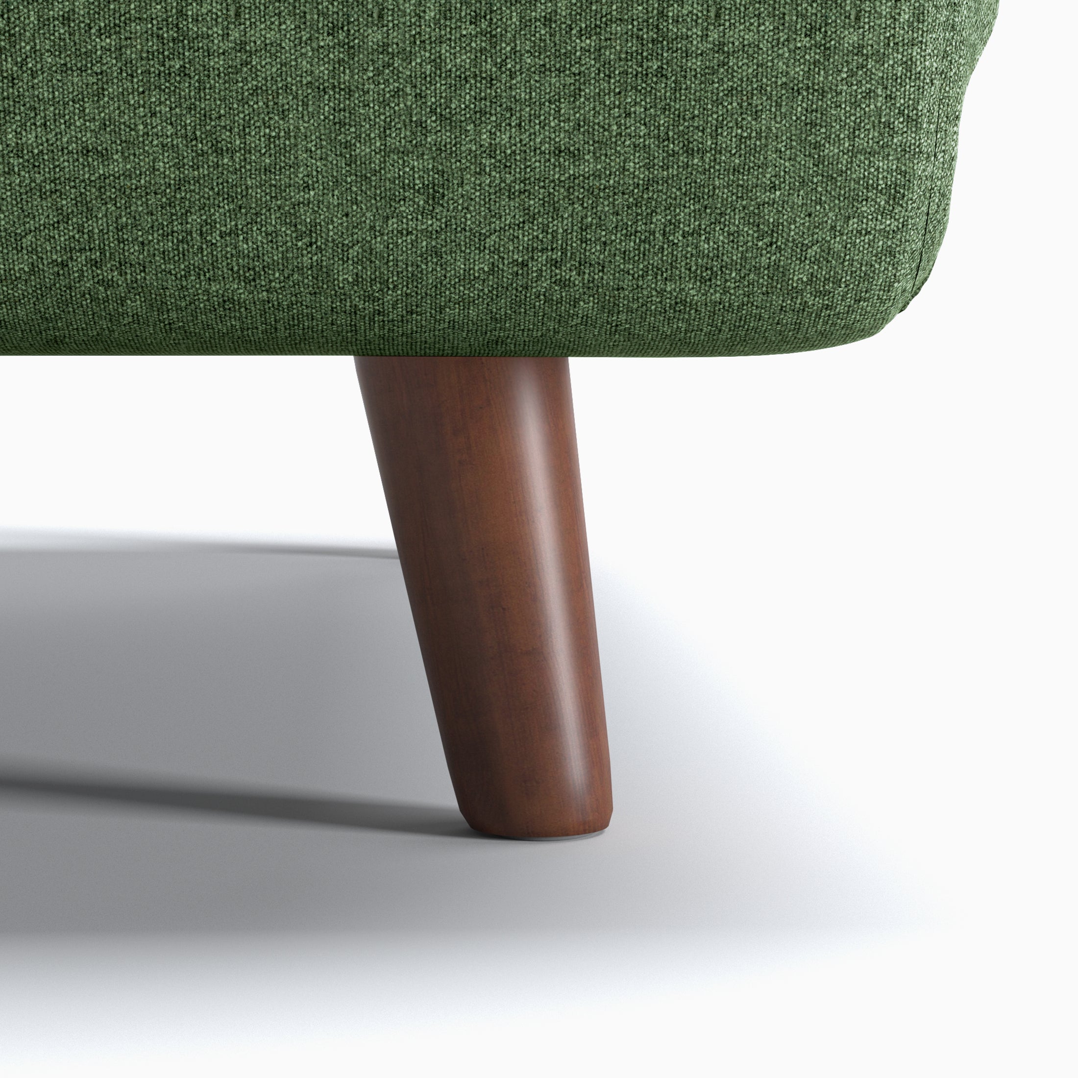 Tustin Convertible Chair in Green featuring a close-up of the tapered dark brown wood leg beneath the rounded base and textured green upholstery.