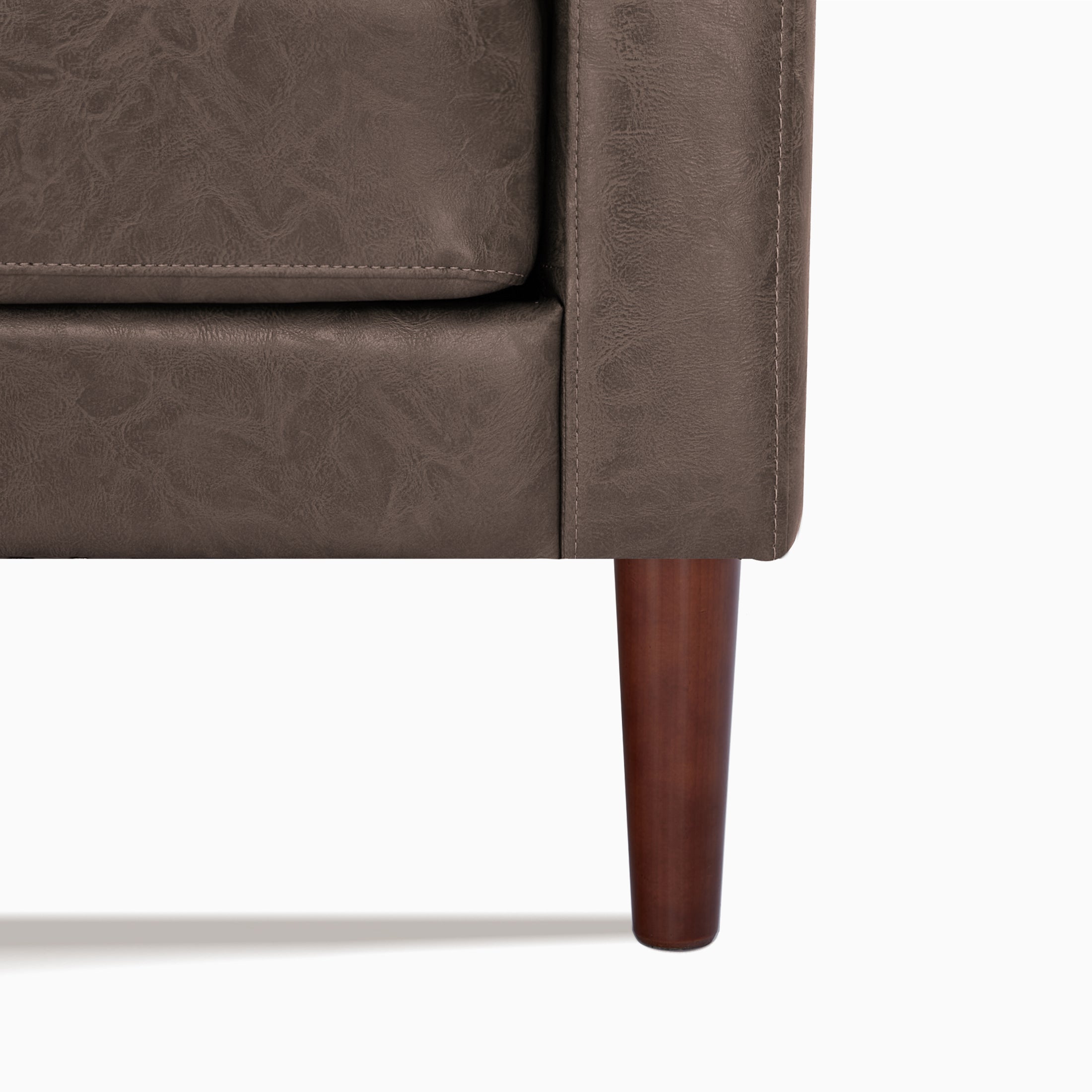 Orlando Loveseat in Faux Leather Brown featuring a close-up of the distressed upholstery, stitched cushion edge, track arm seam, and tapered dark brown leg.