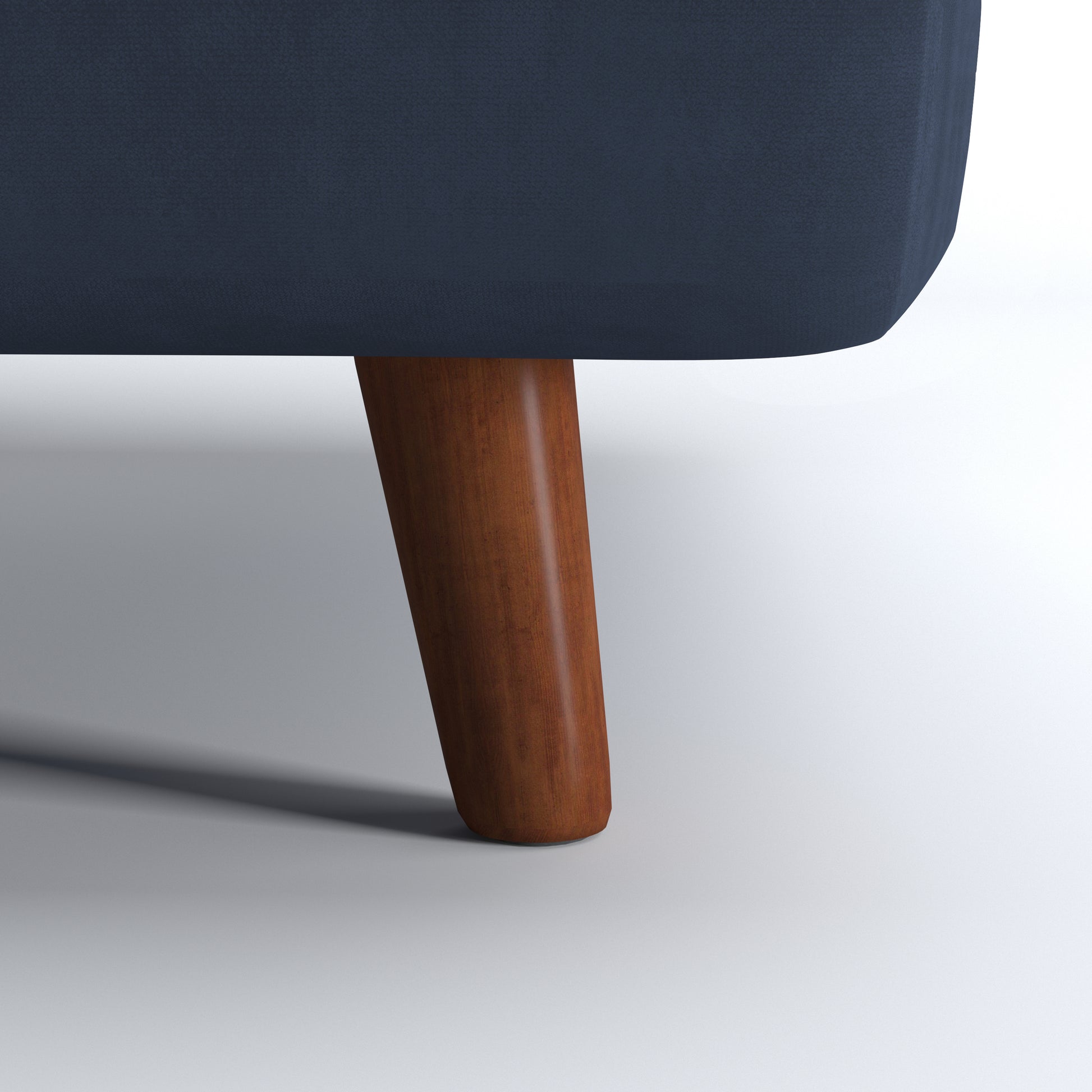 Tustin Convertible Chair in Velvet Blue featuring a close-up of the tapered dark brown wood leg beneath the rounded base and blue velvet upholstery