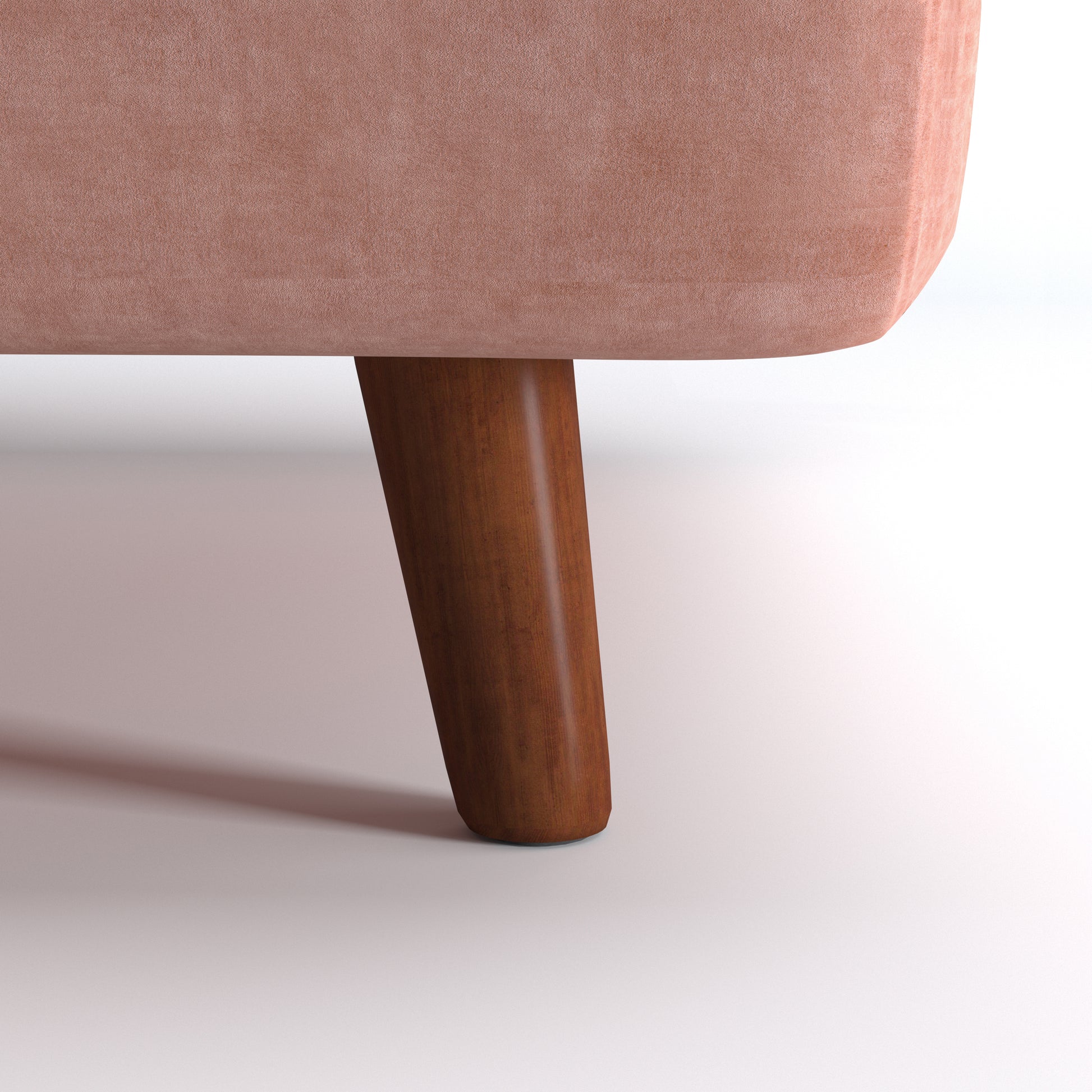 Tustin Convertible Chair in Velvet Blush featuring a close-up of the tapered dark brown wood leg beneath the rounded base and blush velvet upholstery.