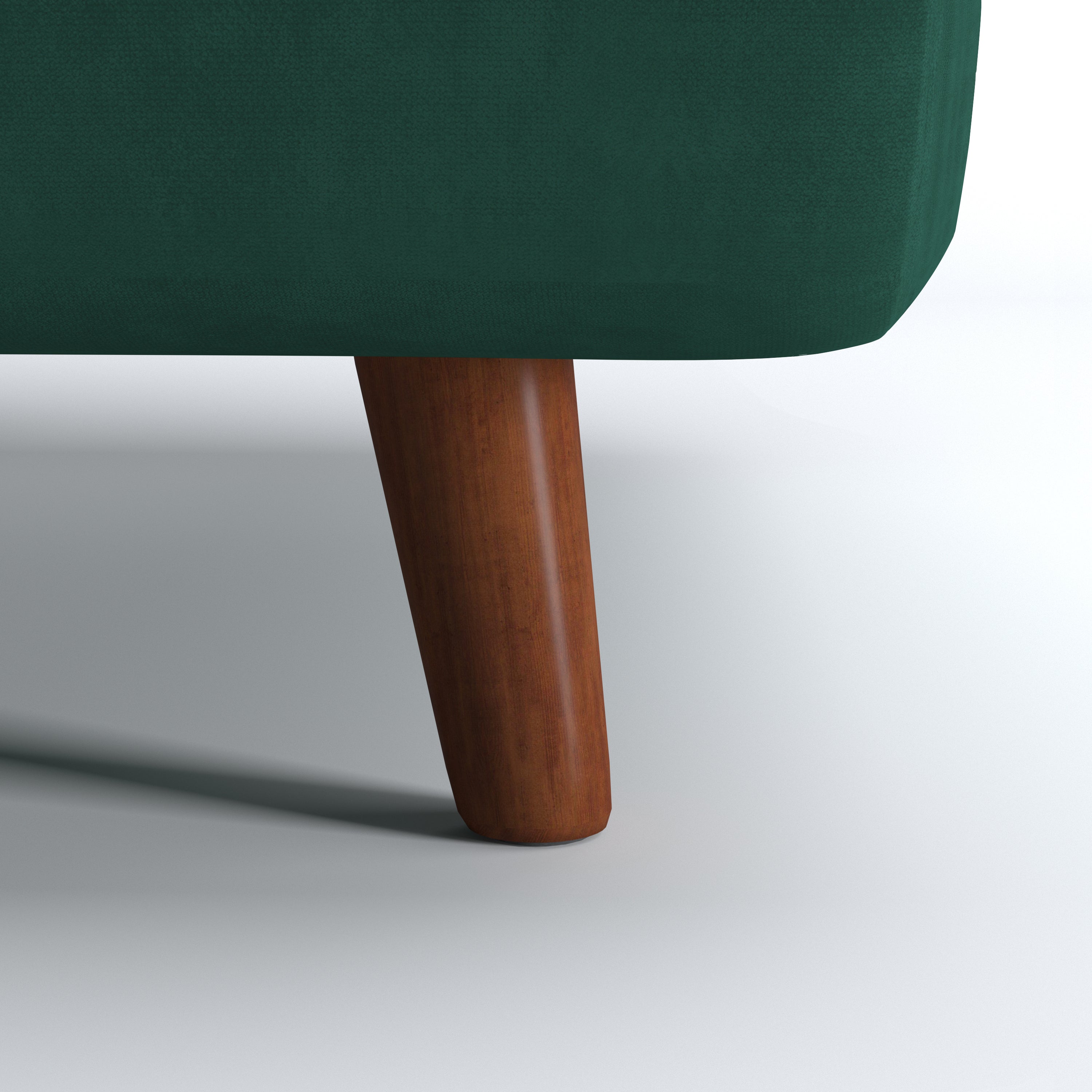 Tustin Convertible Chair in Velvet Green featuring a close-up of the tapered dark brown wood leg beneath the rounded base and green velvet upholstery.