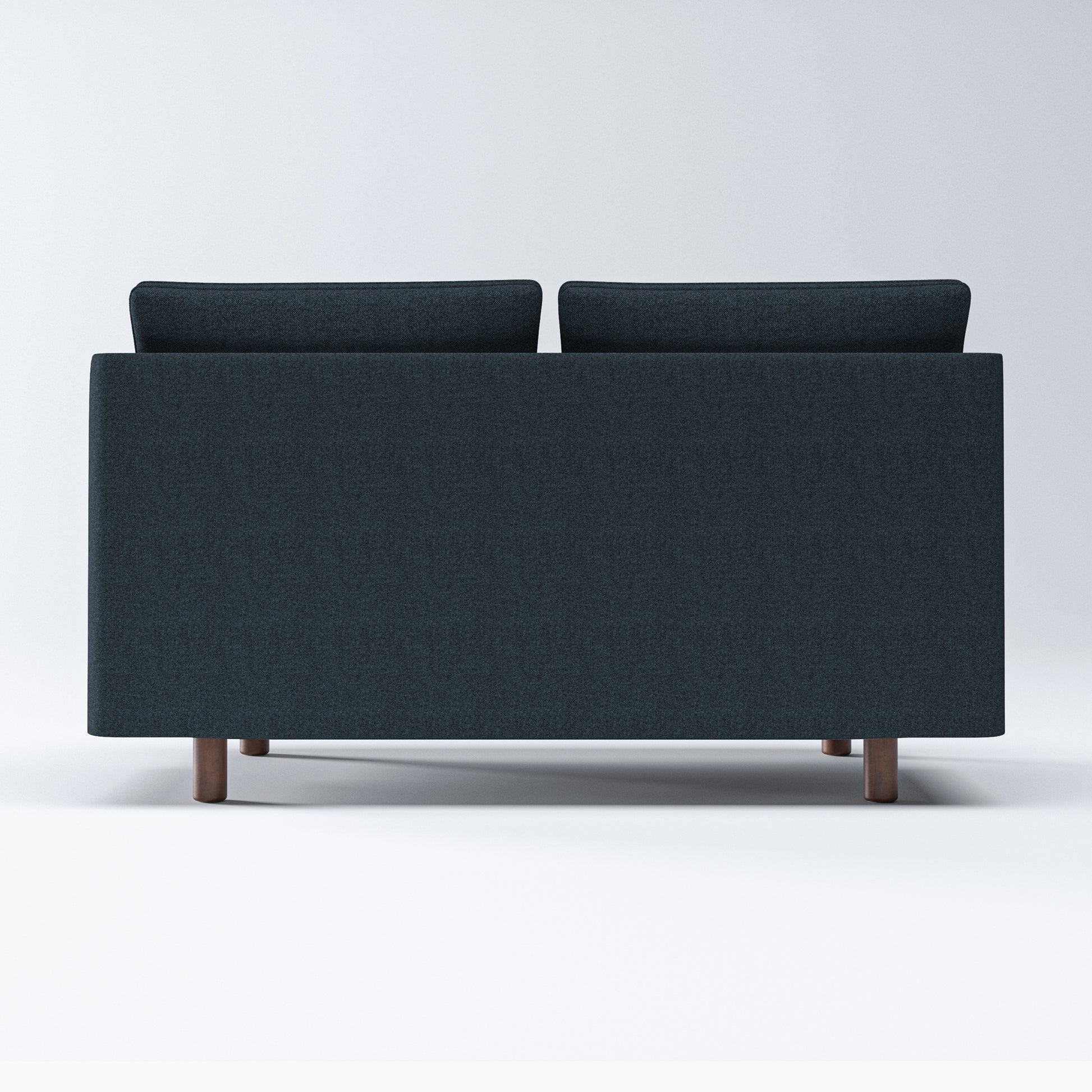 Nora Loveseat in Navy Blue shown from the rear, displaying a broad upholstered back panel, two raised back cushions, and short brown cylindrical legs.