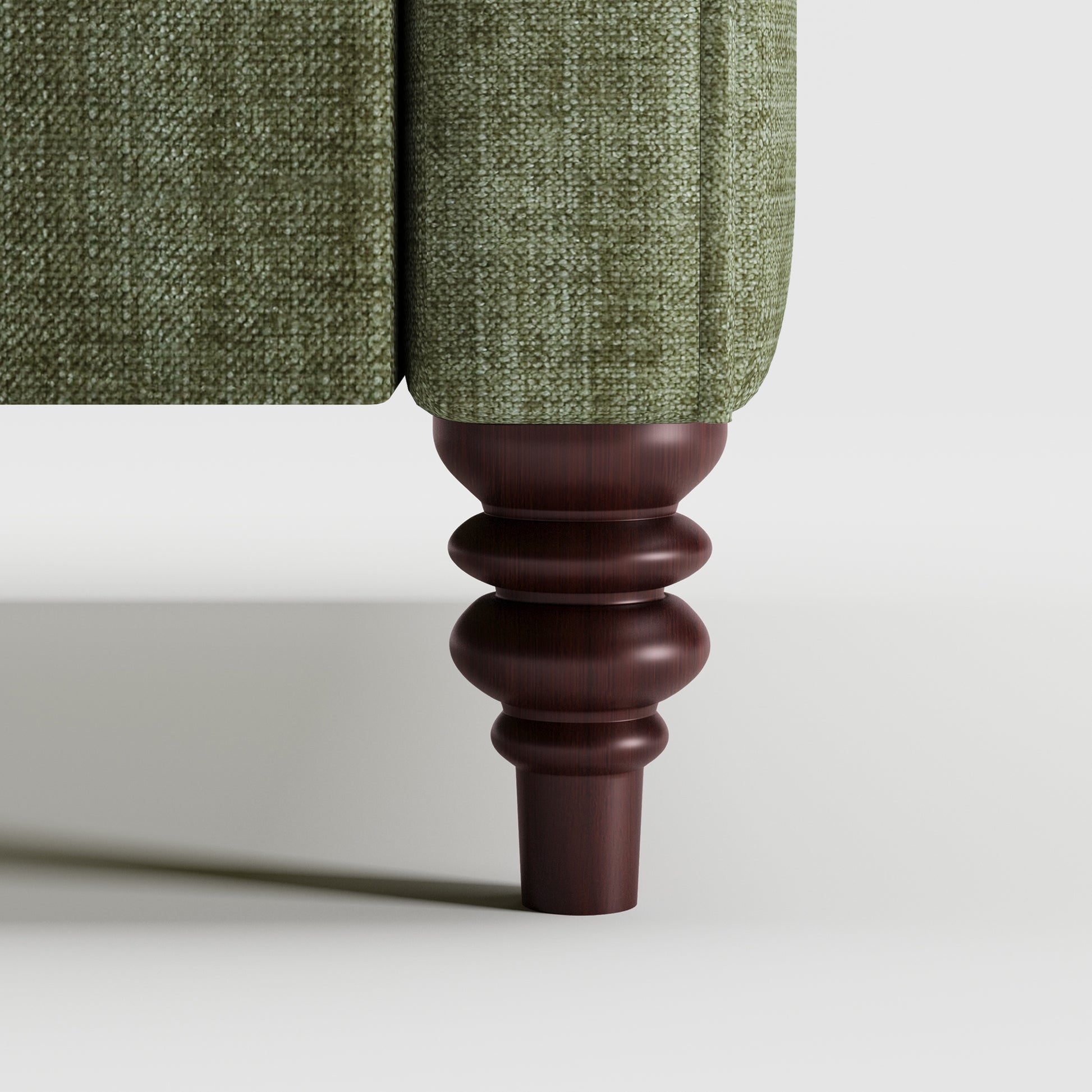 Madison Loveseat in Sage Green featuring a close-up of the decorative turned dark brown leg beneath the upholstered arm and textured sage green fabric.