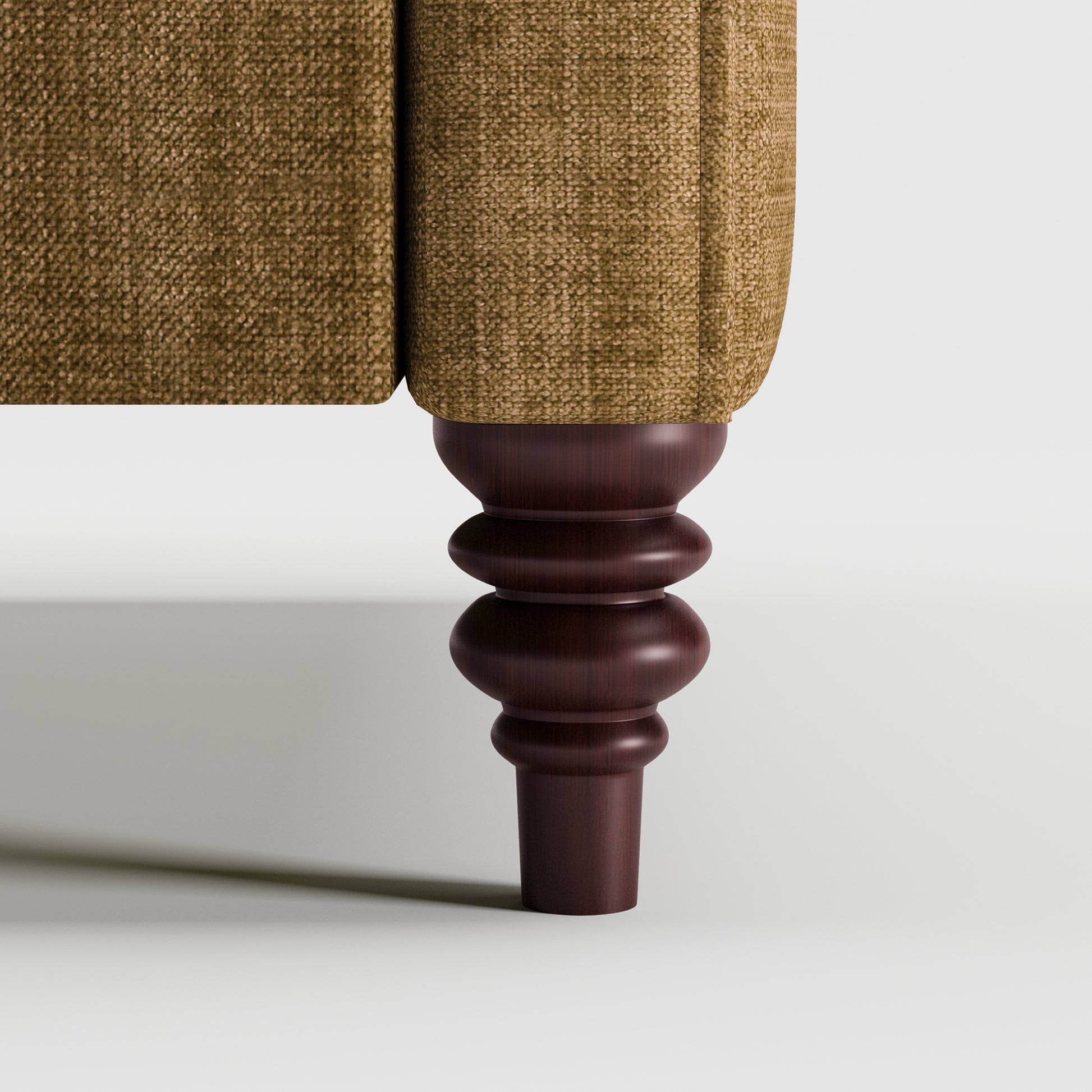 Madison Loveseat in Caramel Brown featuring a close-up of the decorative turned dark brown leg beneath the upholstered arm and textured caramel brown fabric.