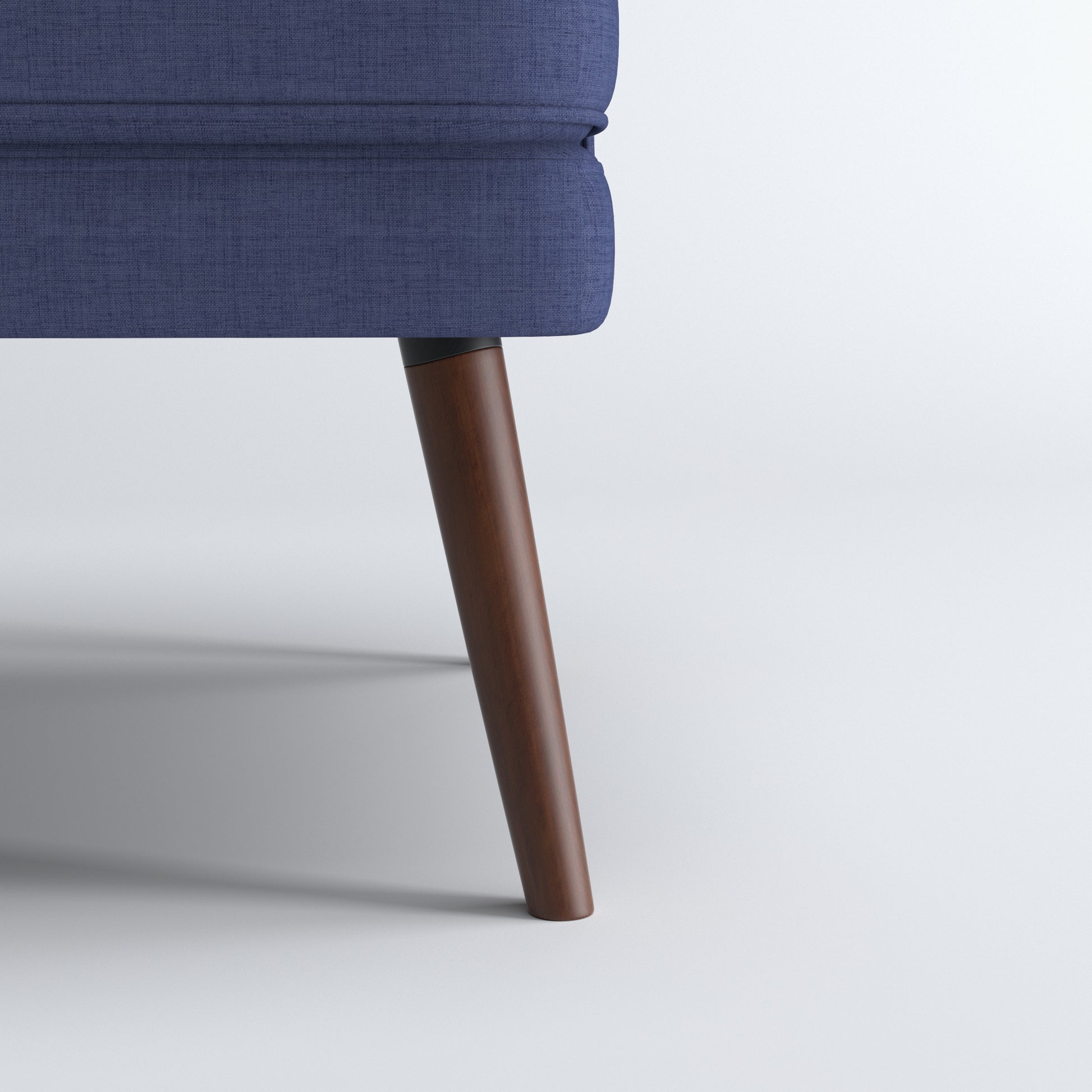 Dana Accent Chair in Faux Linen Blue featuring a close-up of one tapered brown leg beneath the rounded upholstered base and textured faux linen fabric