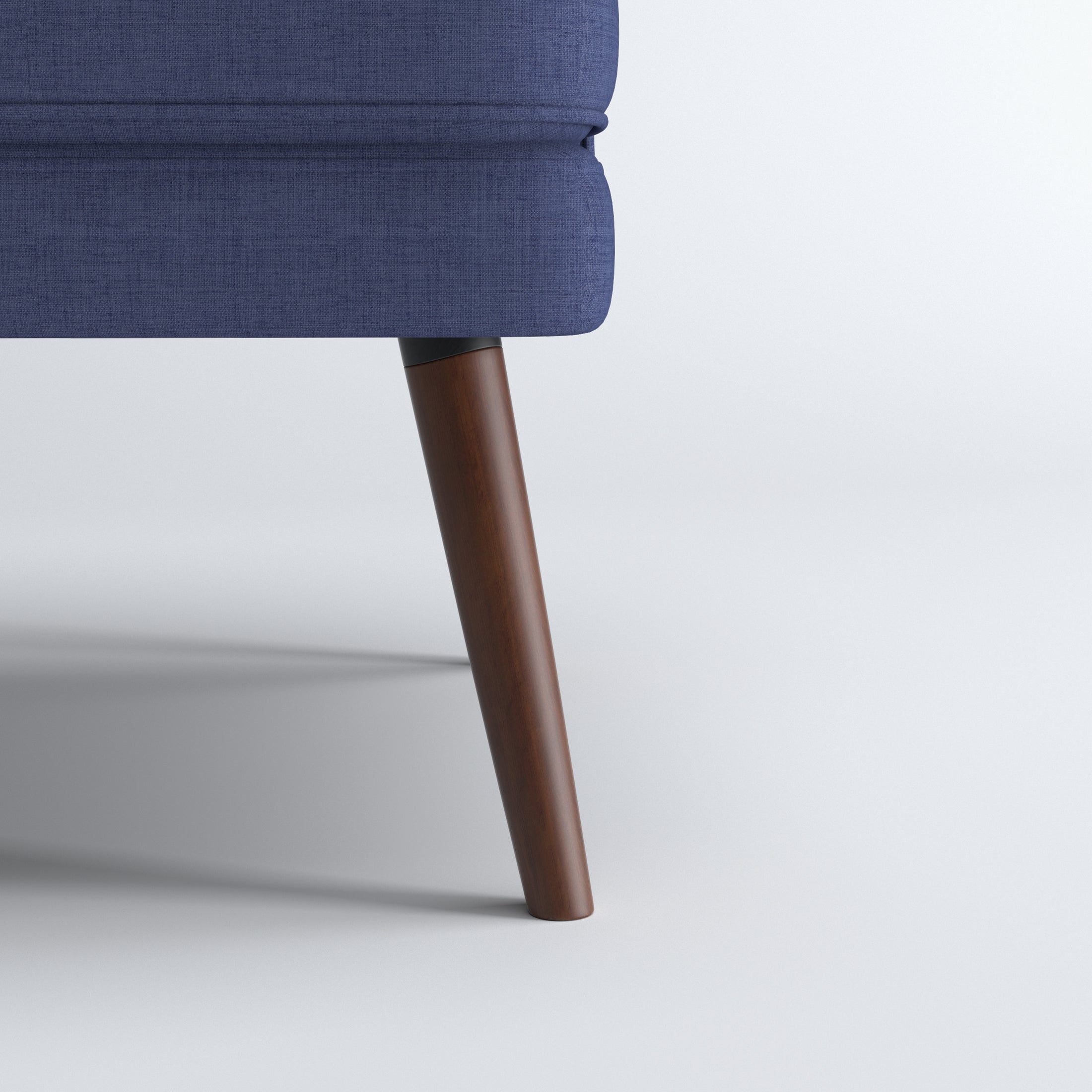 Dana Accent Chair in Faux Linen Blue featuring a close-up of one tapered brown leg beneath the rounded upholstered base and textured faux linen fabric