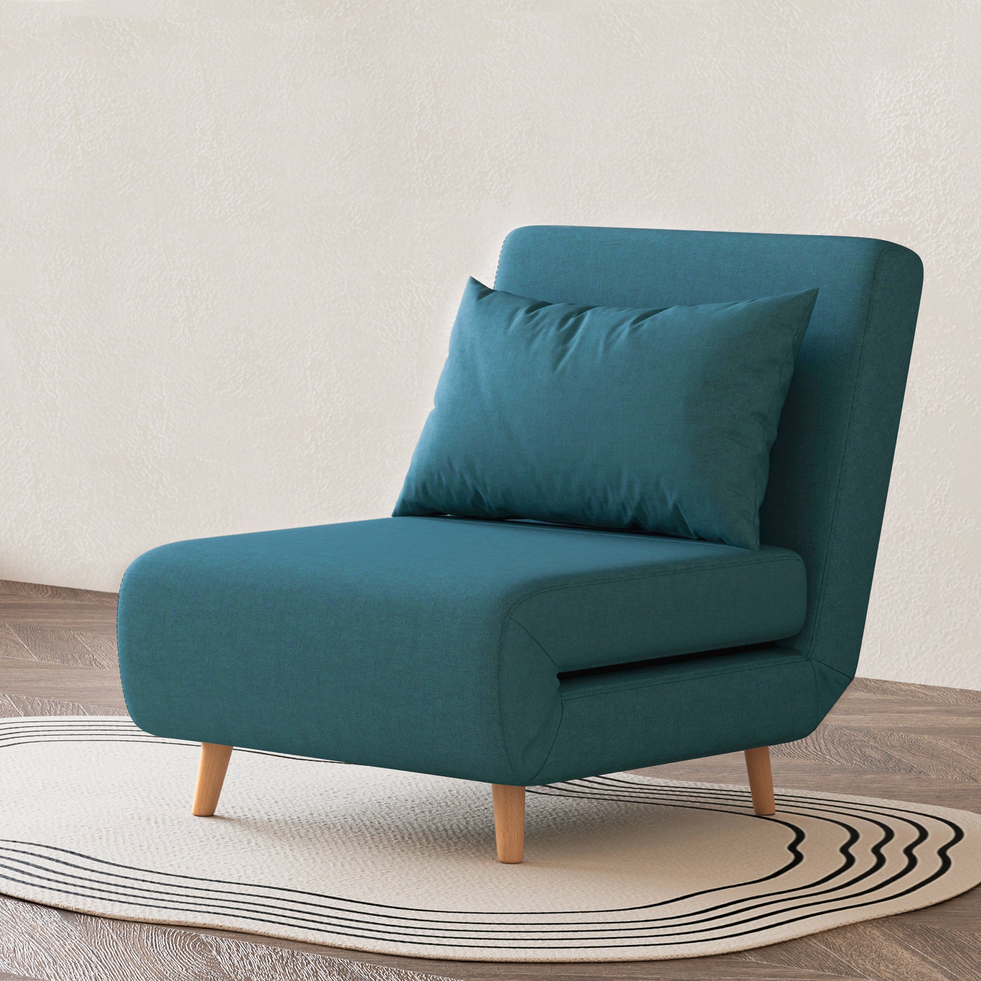 Tustin Convertible Chair in Peacock Blue styled on a patterned rug with an armless silhouette, matching lumbar pillow, rounded seat, and tapered natural wood legs.