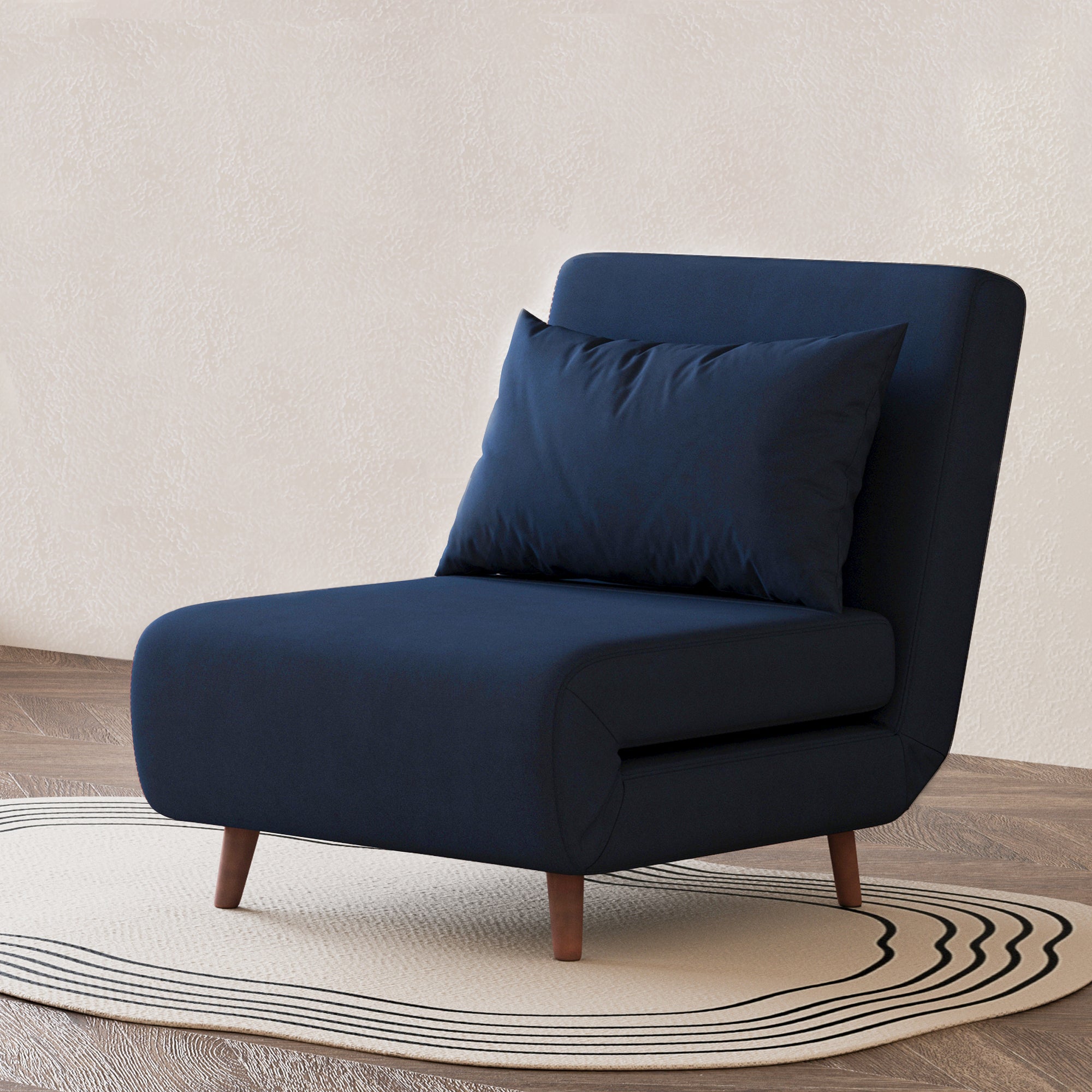 Tustin Convertible Chair in Velvet Blue styled on a patterned rug with an armless silhouette, matching lumbar pillow, rounded seat, and tapered dark brown wood legs.