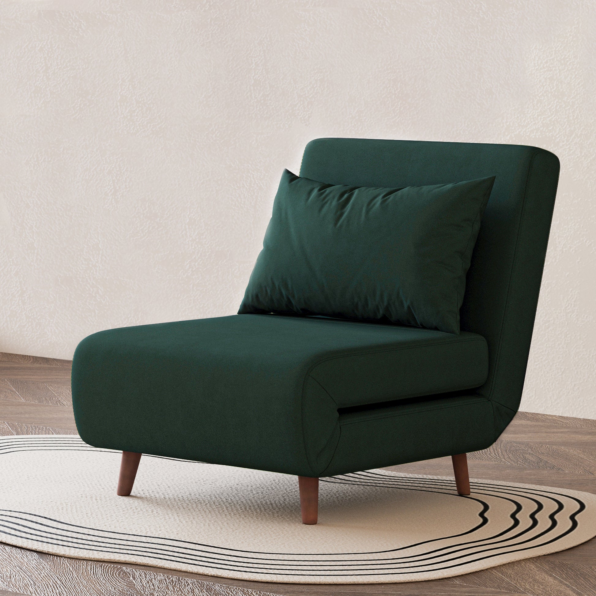 Tustin Convertible Chair in Velvet Green styled on a patterned rug with an armless silhouette, matching lumbar pillow, rounded seat, and tapered dark brown wood legs.