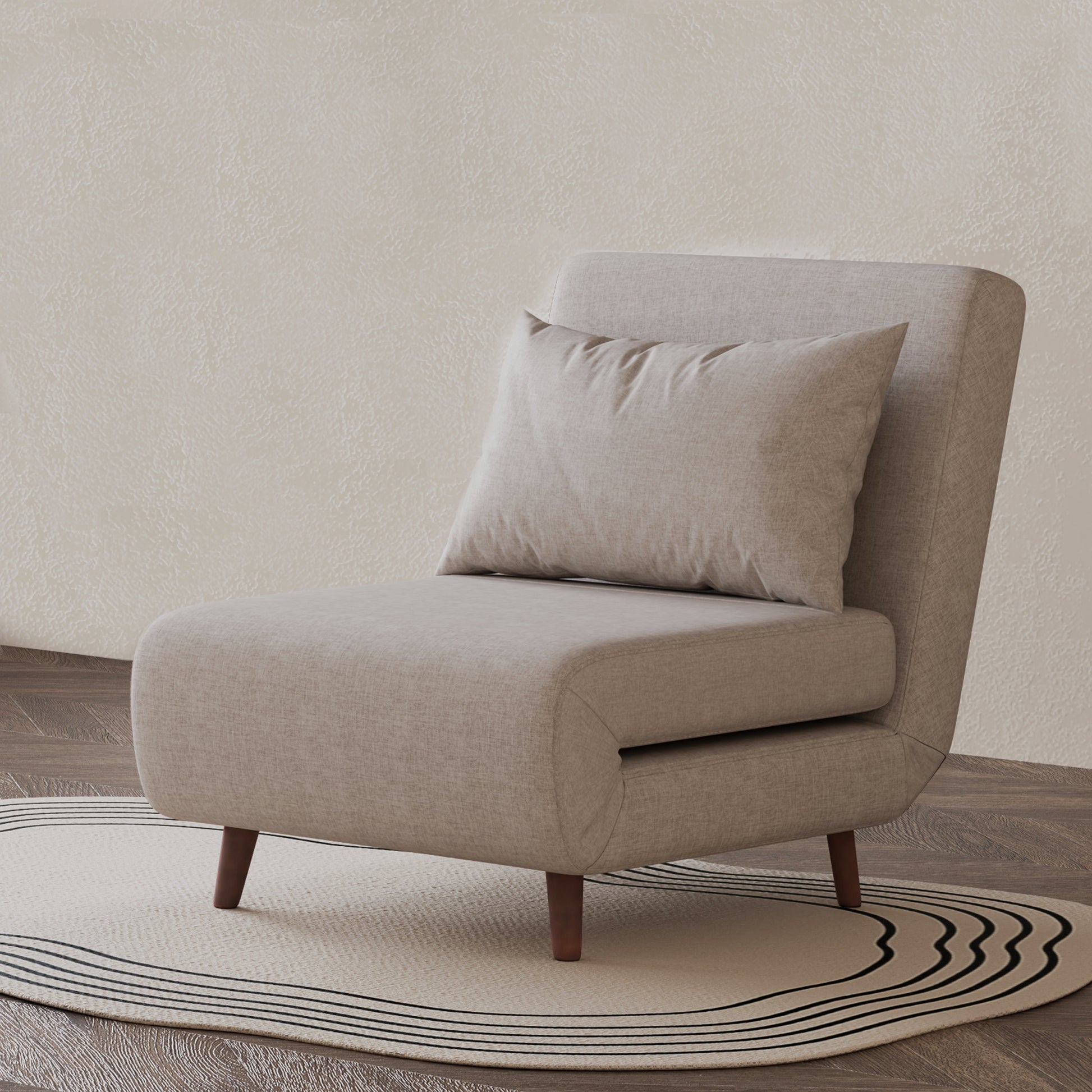 Tustin Convertible Chair in Beige styled on a patterned rug with an armless silhouette, matching lumbar pillow, rounded seat, and tapered dark brown wood legs.