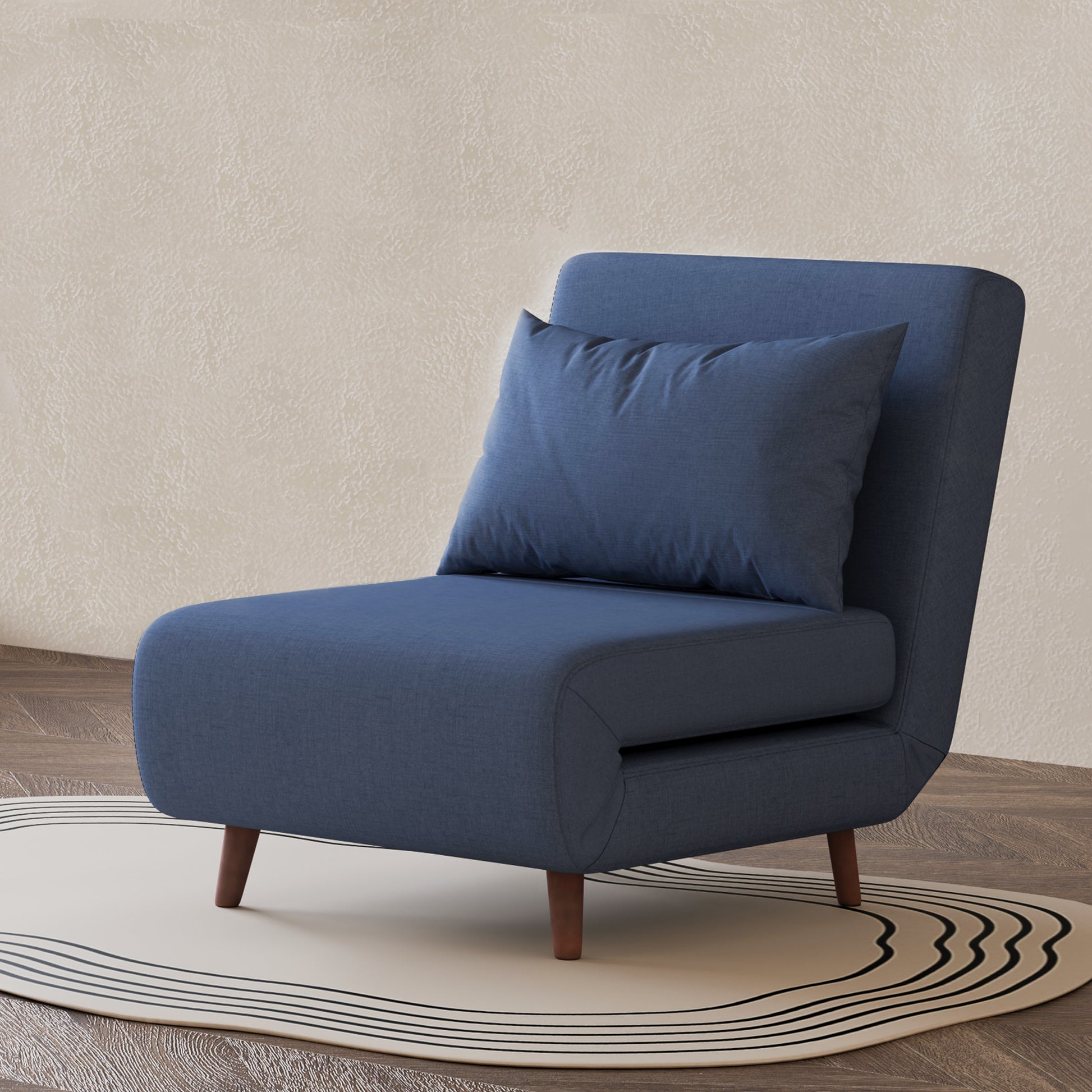 Tustin Convertible Chair in Blue styled on a patterned rug with an armless silhouette, matching lumbar pillow, rounded seat, and tapered dark brown wood legs.